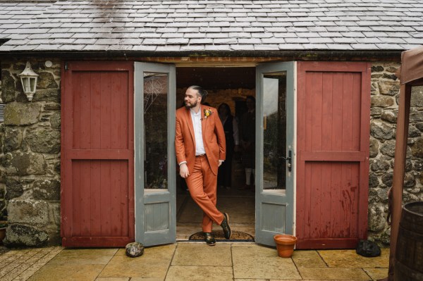 Groom leans against doorframe