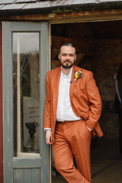 Groom leans against doorframe