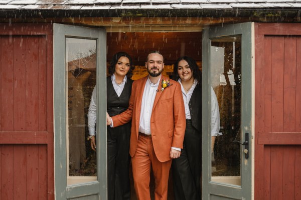 Groom and two women exit house at doorframe