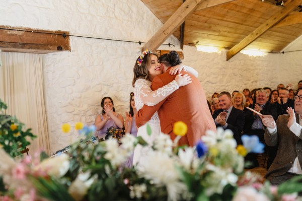 Bride and groom go in for a hug at alter