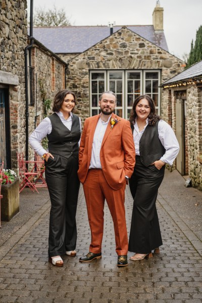 Groom and two sisters women smiling in suits