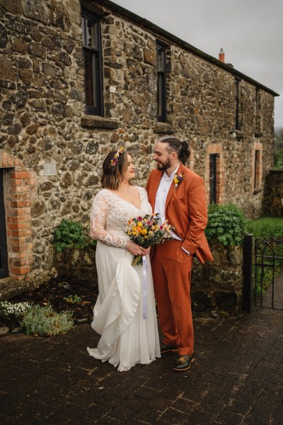 Bride and groom are standing outside looking at each other