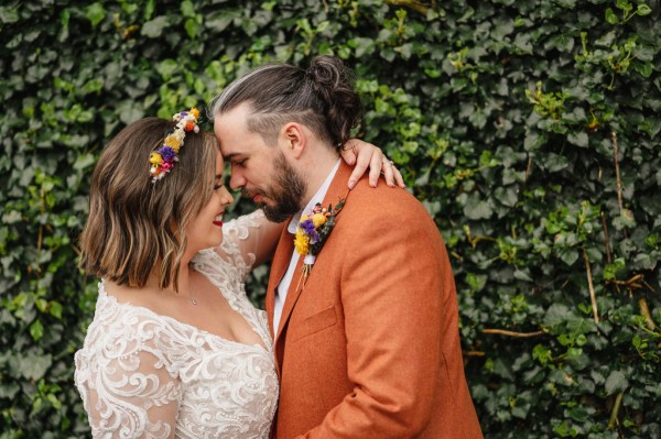 Bride and groom touch foreheads in garden setting