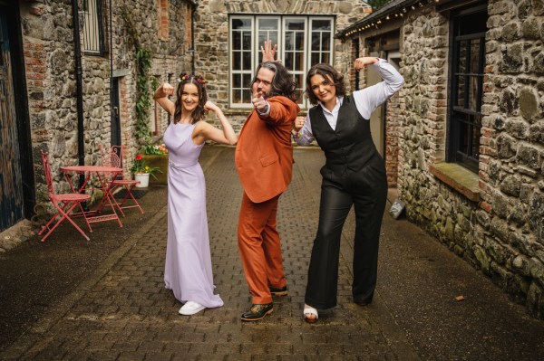 Bridesmaids groom and woman all pose in courtyard