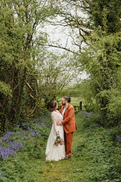 Bride and groom face each other in garden forest setting green grass they kiss