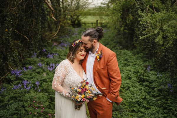 Bride and groom embrace in forest setting