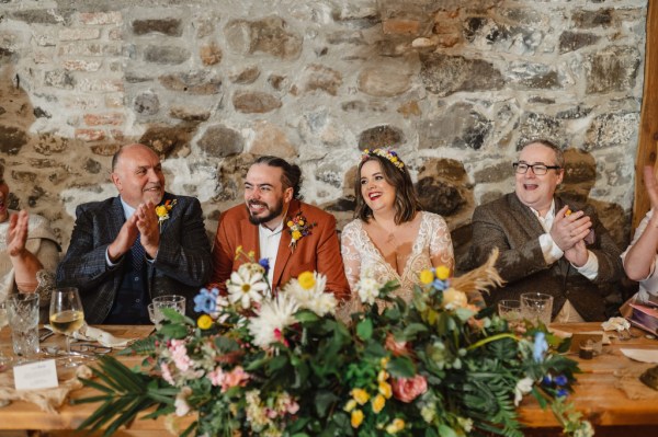 Bride groom and father sit listening to speeches