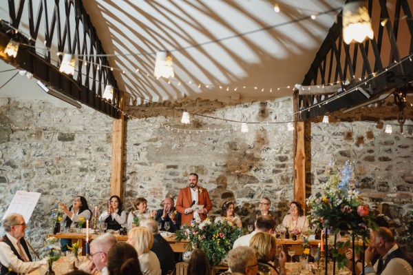 Groom in orange suit gives speech to guests