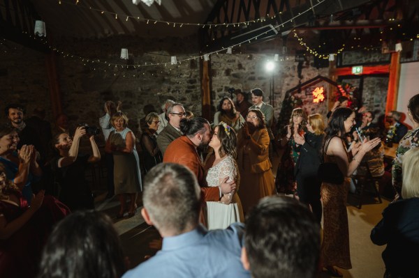 Bride and groom kiss amongst crowd