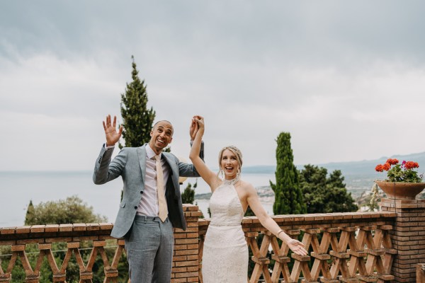 bride and groom at top of wedding venue balcony all smiles celebrating