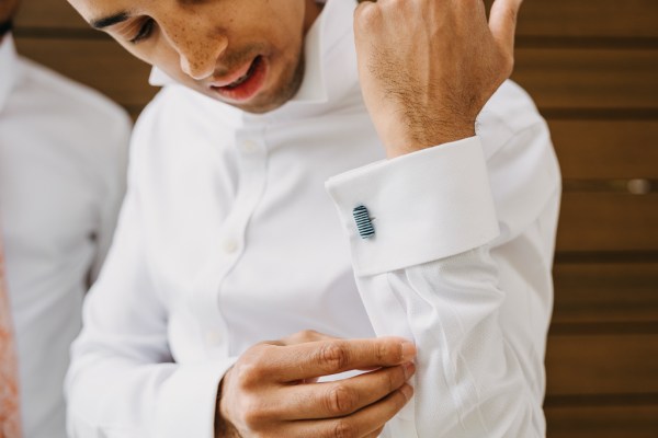 groom fixes up his cufflinks on white shirt