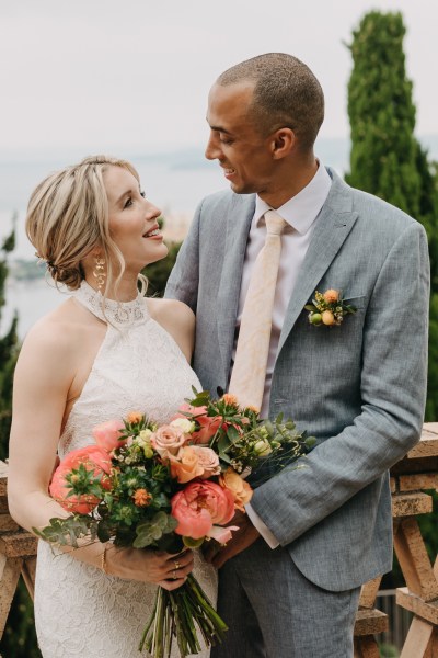 bride and groom look at each other she holds bouquet of flowers