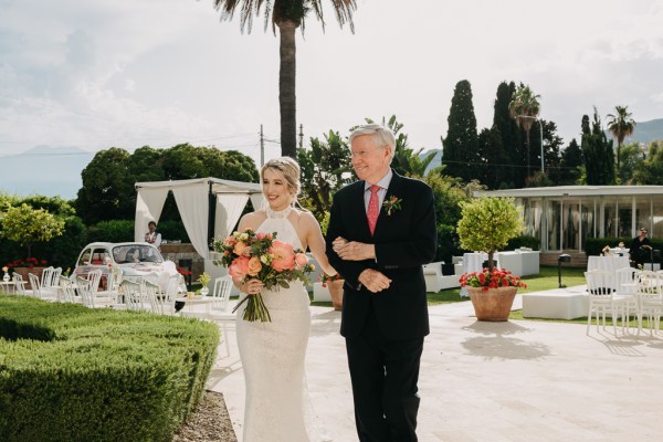 father of the bride and daughter walk towards the ceremony