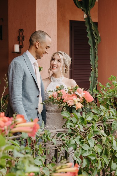 bride and groom stand looking at each other surrounded by flowers