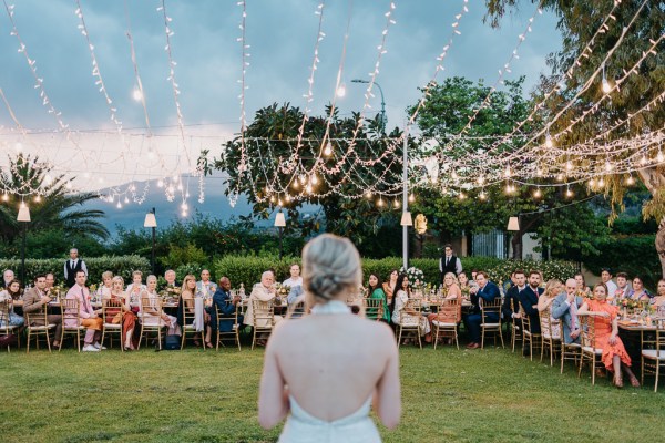 bride from behind guests looking at her fairy lights above