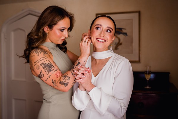 Bridesmaids covered in tattoos helps bride with earrings