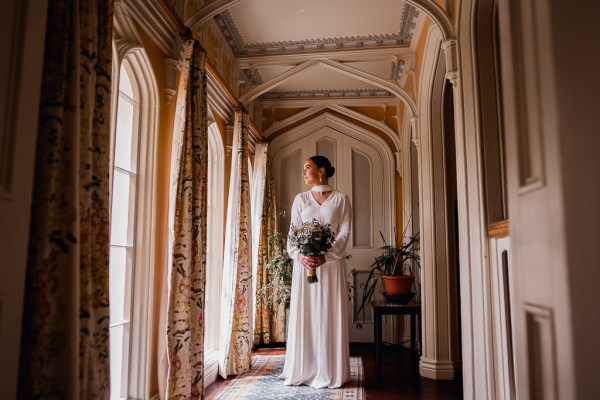 Bride looks out of window holding bouquet