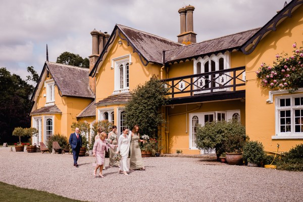 Exterior shot of bride and mother walking to ceremony yellow venue