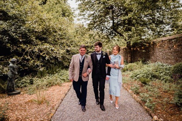 Mother father and son groom walk down the pathway