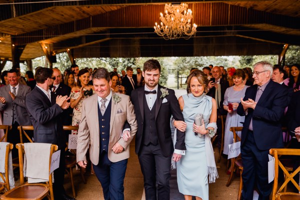 Mother and father walk son groom down the aisle