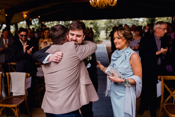 Groom hugs father emotional mother