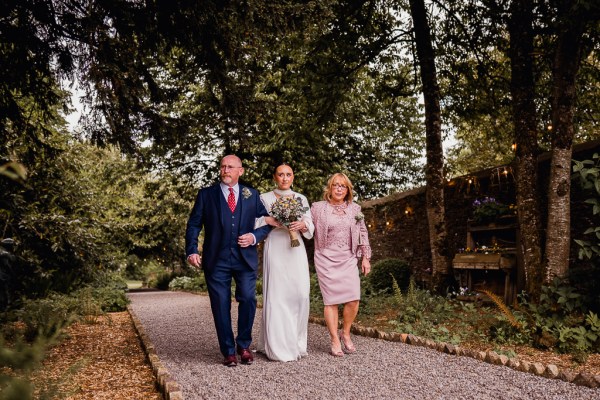 Father and mother walk daughter bride towards the ceremony