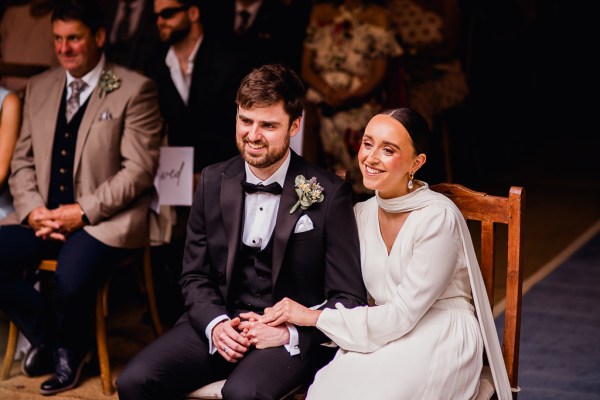 Bride groom sitting down at alter setting smiling laughing