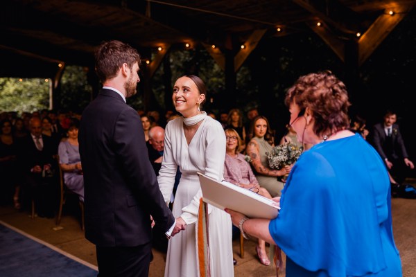 Celebrant holds ribbon bride and groom laugh at alter