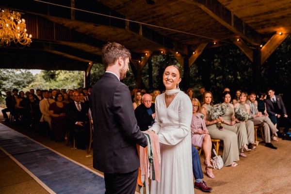 Bride and groom smile in front of guests at alter