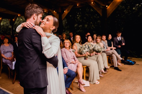 Bride and groom embrace hug in front of guests