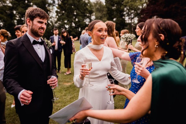 Bride and groom gesture to guests bride goes in for a hug