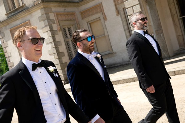 Groom and groomsmen walk the venue courtyard wearing sunglasses shades