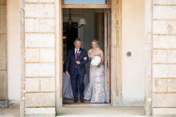 Father of the bride emerge from the castle venue entrance mid shot