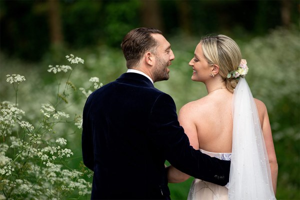 From behind bride and groom veil they look at each other