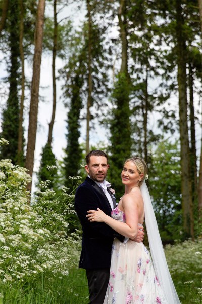 Bride and groom embrace in forest area