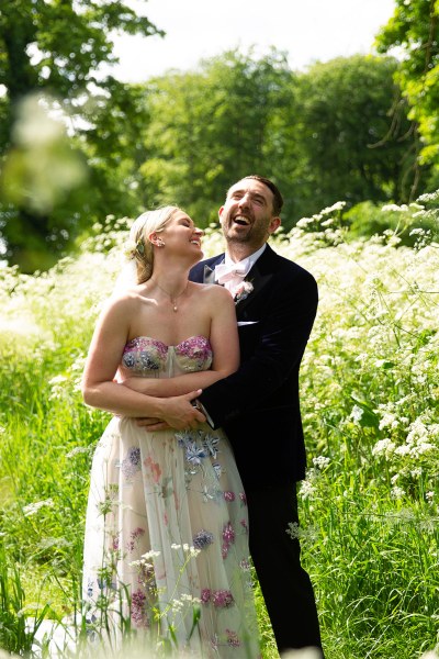 Bride and groom embrace hug in garden park kiss on the cheek