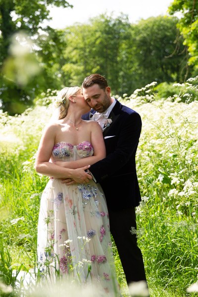 Bride and groom embrace hug in garden park kiss on the cheek