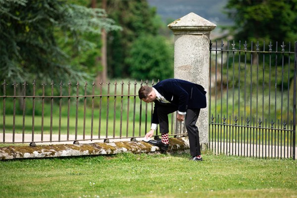 Groom picks up flower from grass garden area