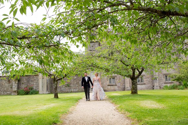 Bride and groom walk down pathway to forest garden park setting