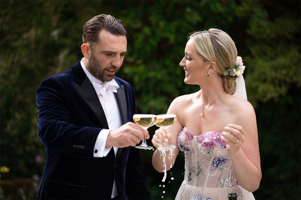 Bride and groom drinking glasses of prosecco it's spilling