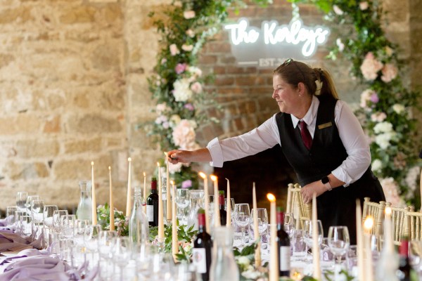 Waiter lights the candles on the tables