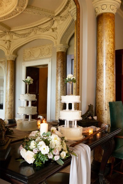 White cake in mirror reflection wedding on table with white flowers