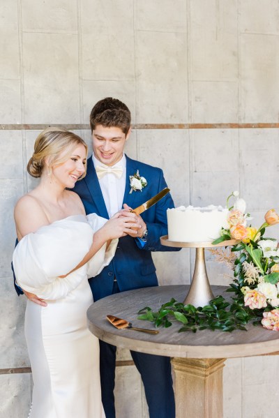 Bride and groom cut the white wedding cake together