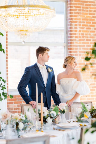 Bride and groom laugh holding hands at dining room table