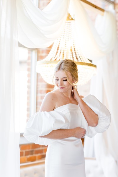 Bride touches back of neck puffy arm sleeves on bridal gown