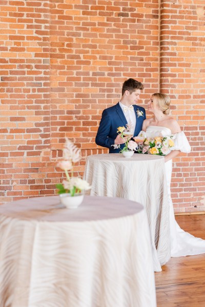 Bride groom beside floral table bouquet they look at each other