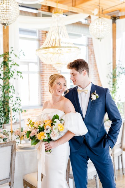 Bride looks over shoulder to groom as they smile she holds bouquet