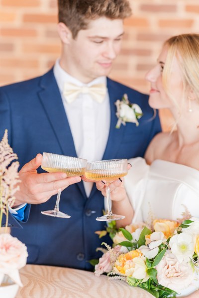 Bride and groom look at each other as they cheers with glasses of champagne