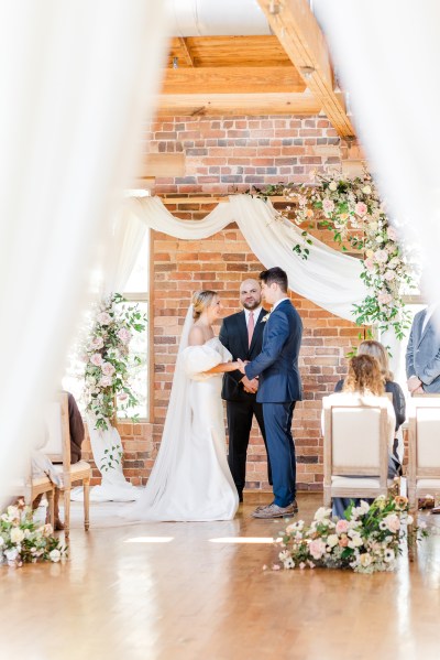 Bride and groom stand at alter in front of celebrant and guests