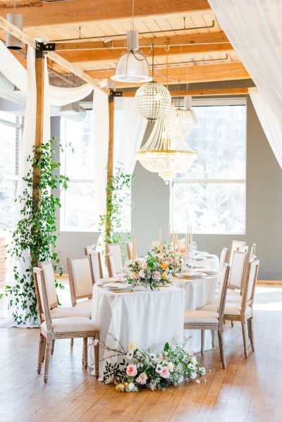 Empty dining room table setting flowers chairs chandelier hanging